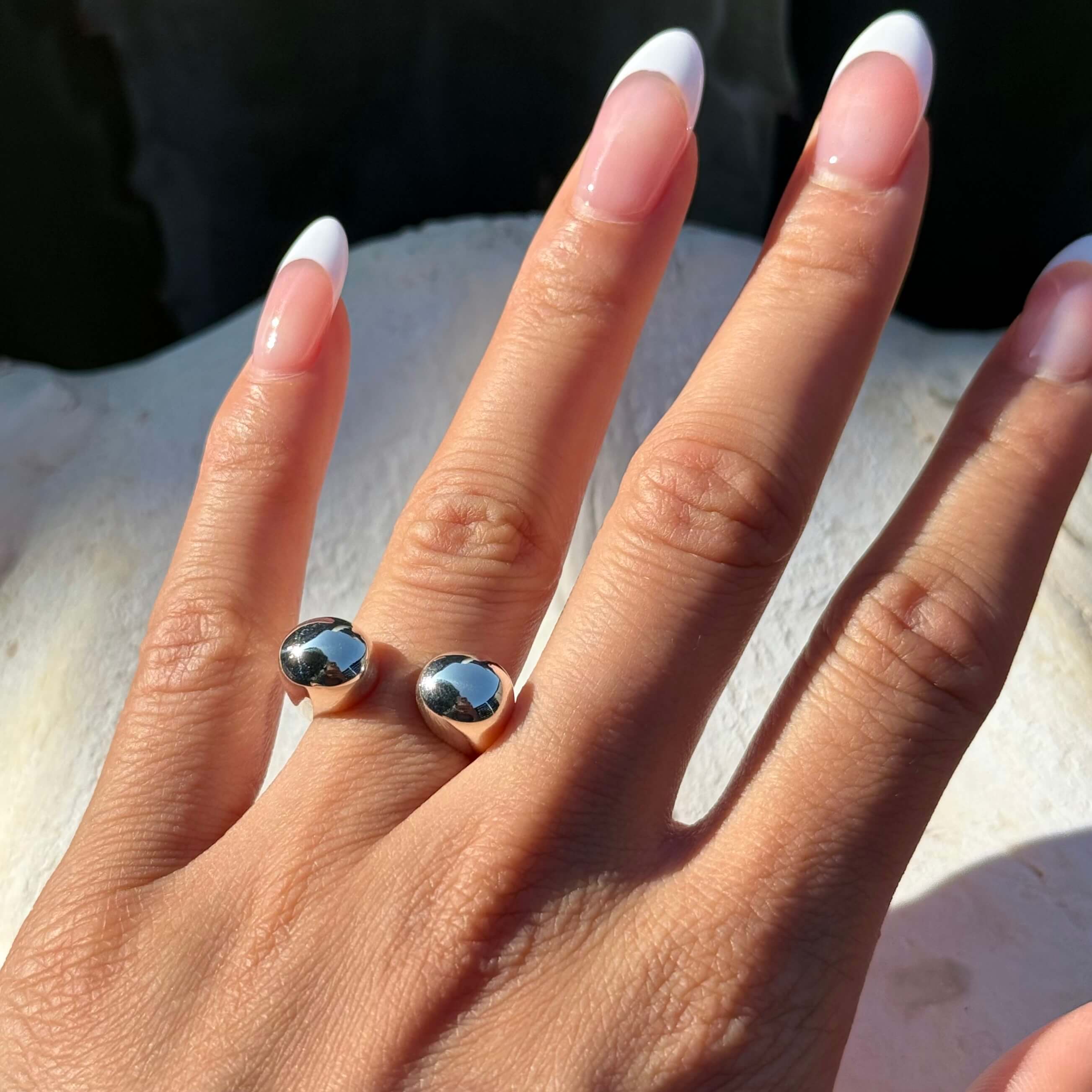 Hand wearing bacll stackable silver ring on a light background