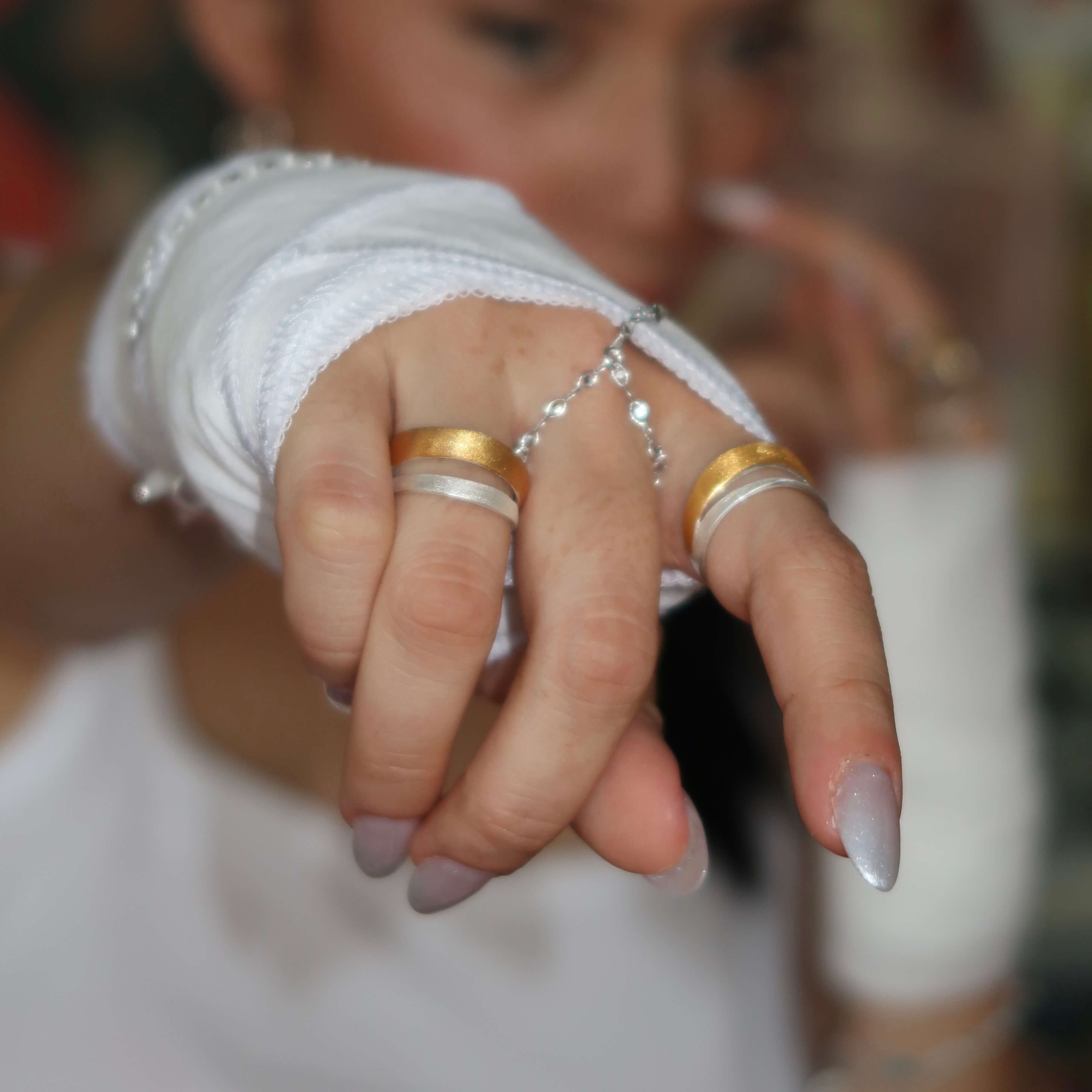 Close-up of a hand wearing multiple duo tone rings with a blurred background