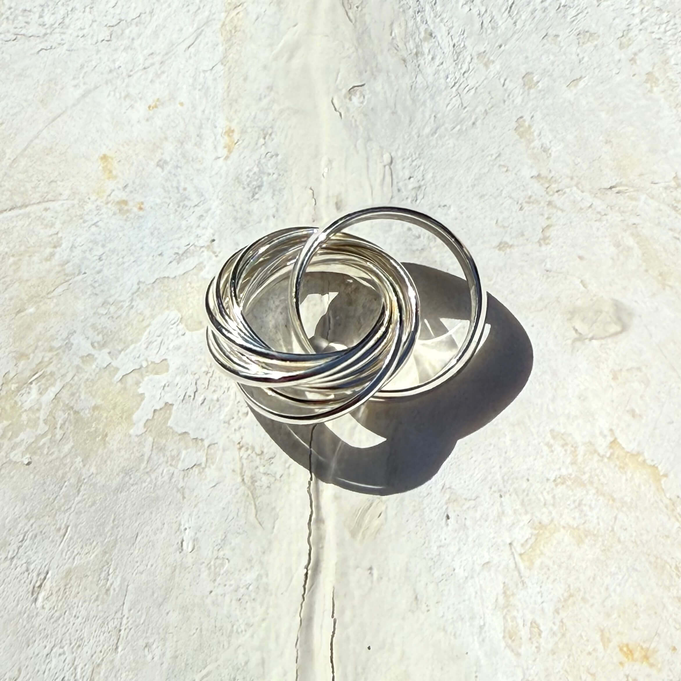Silver rings stacked on a textured white surface