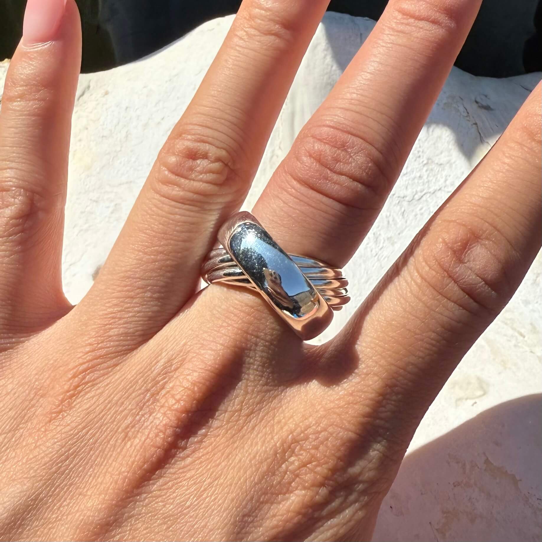 Hand wearing a silver ring with a blue stone on a light background