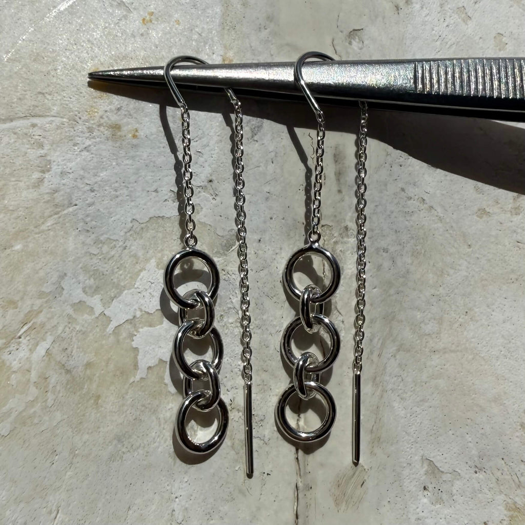 Pair of silver chain earrings on a stone surface