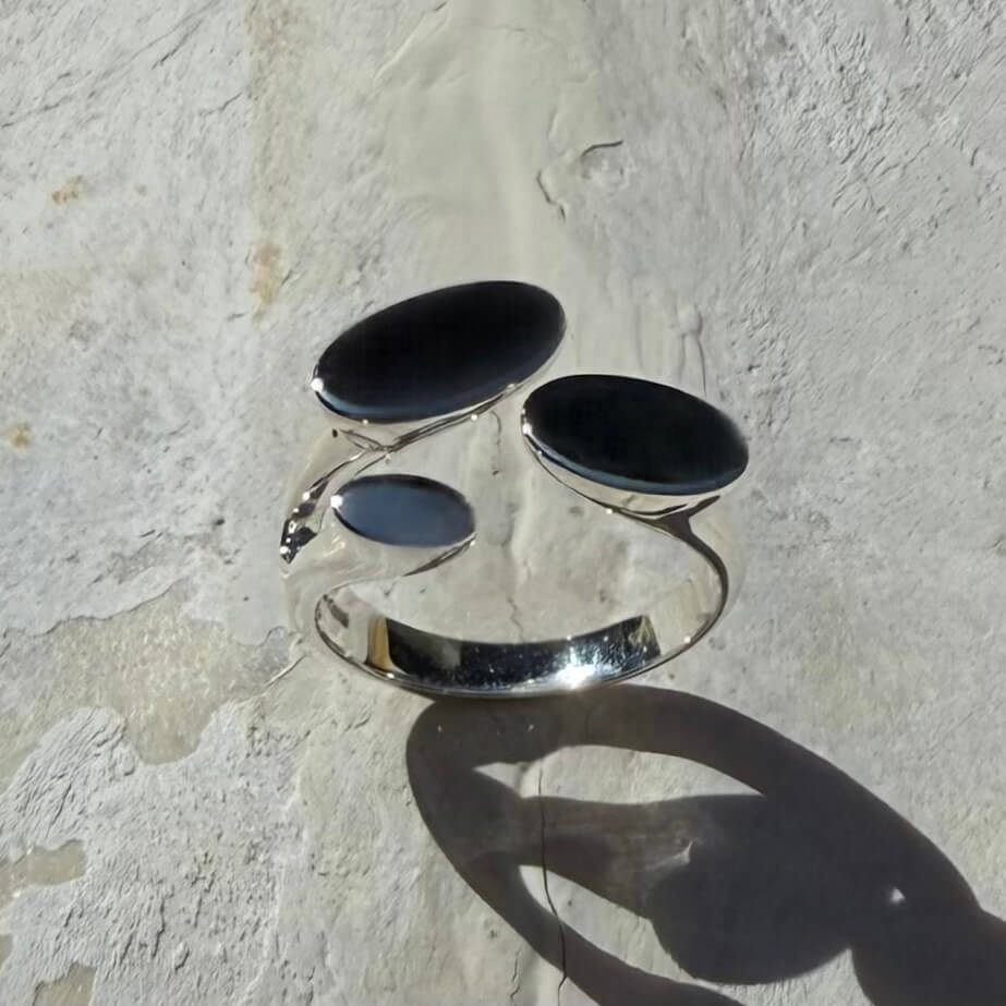 Silver ring with black stones on a textured stone surface