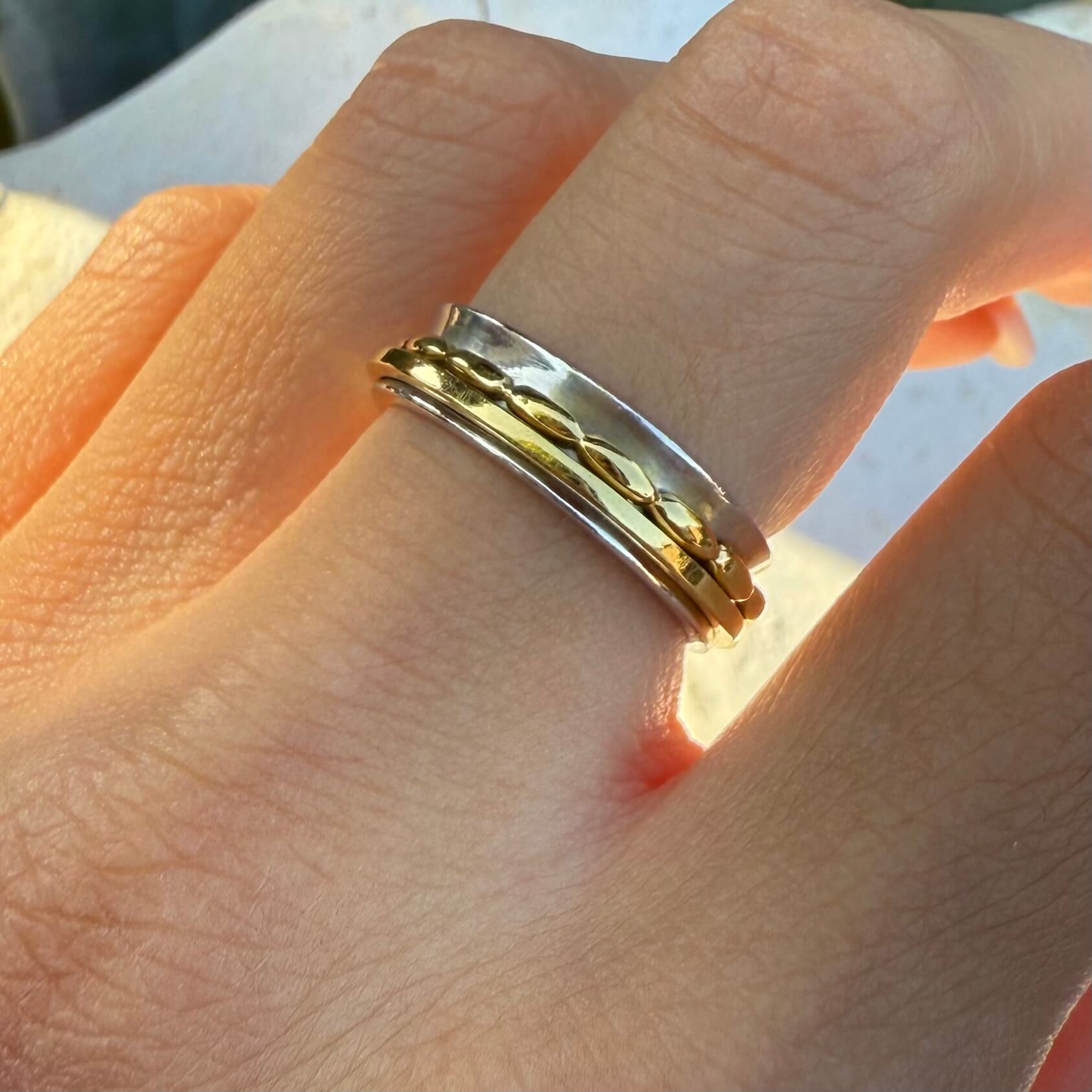 Gold and silver ring on a finger with a blurred background