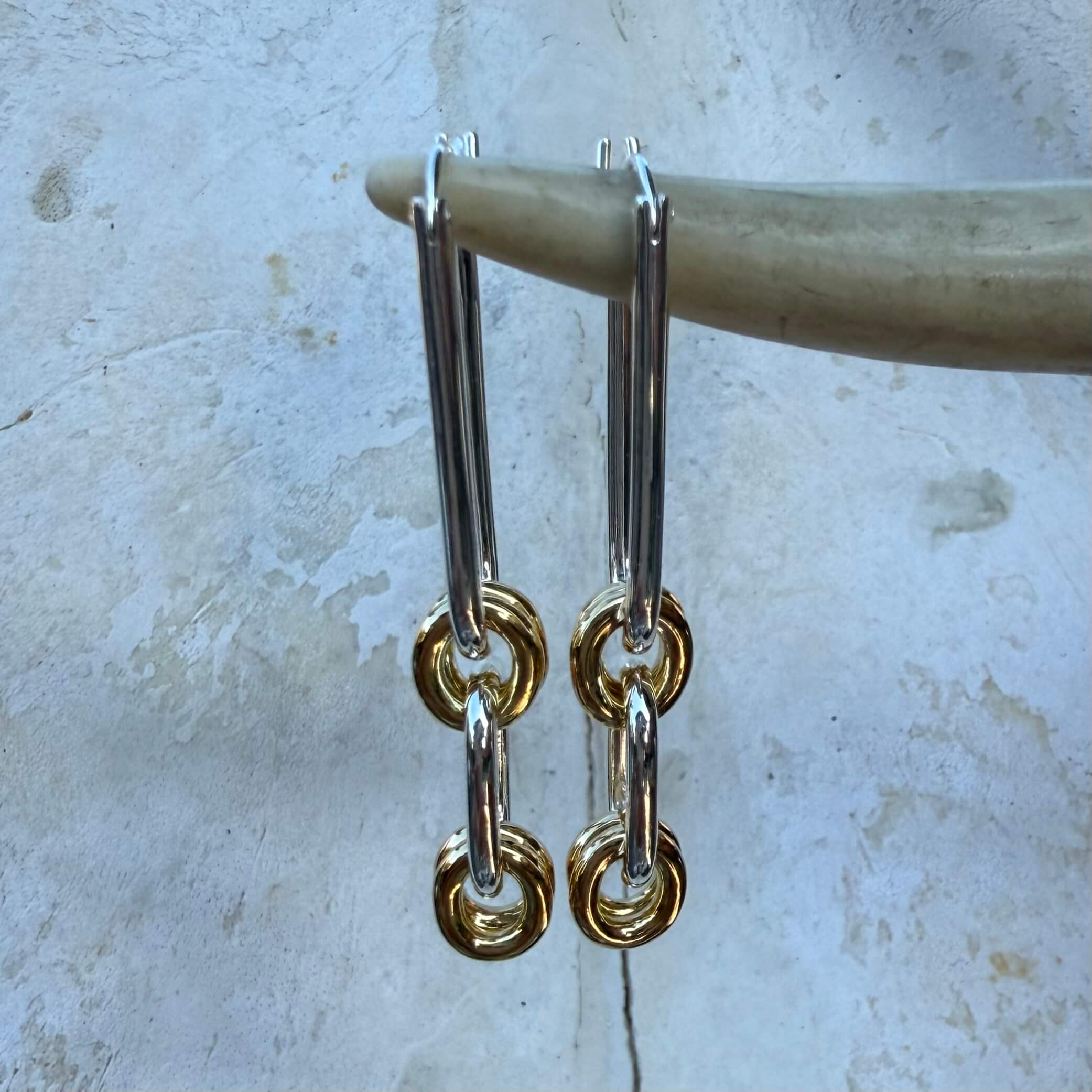 Pair of gold and silver chain earrings on a textured surface