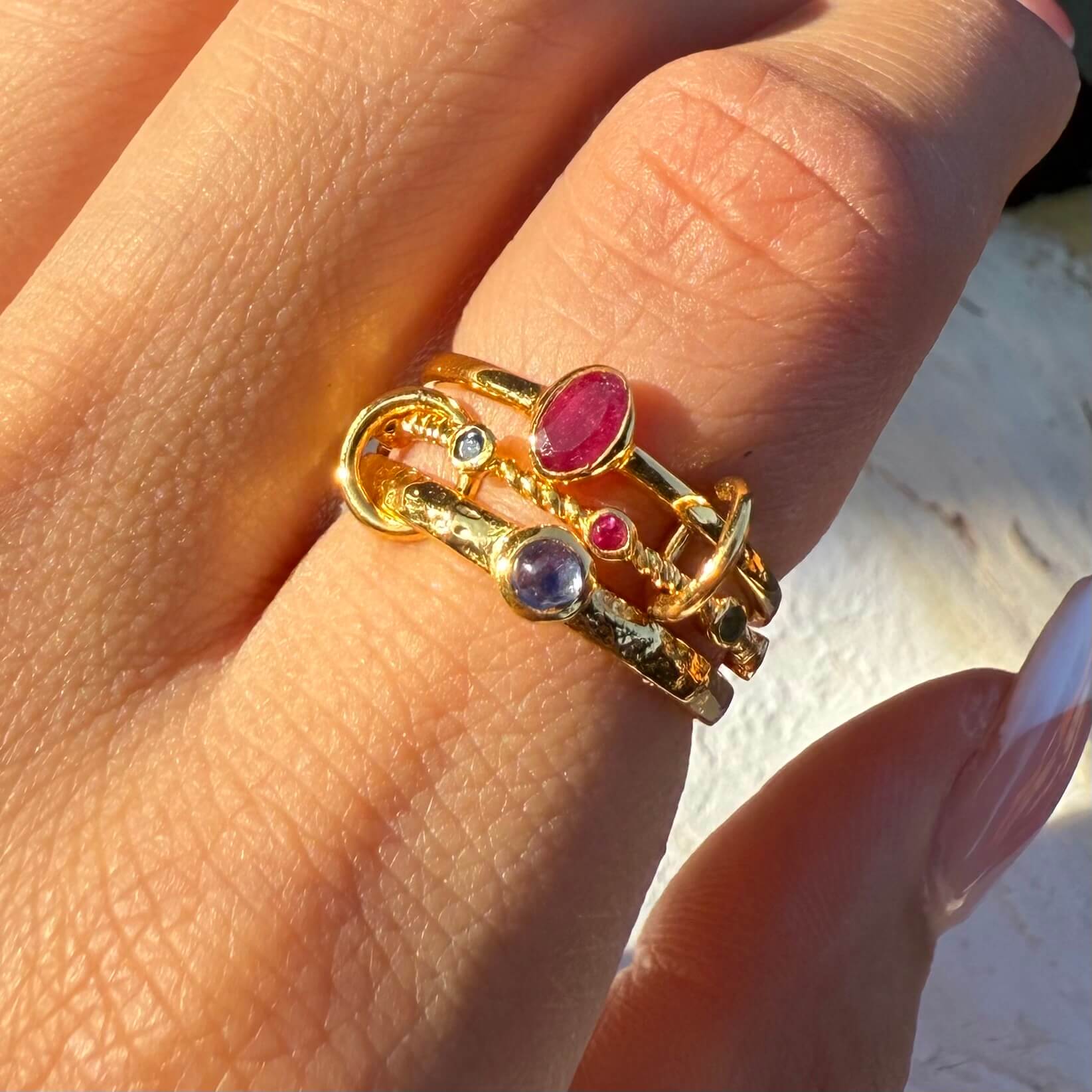 Gold ring with gemstones on a finger against a blurred background