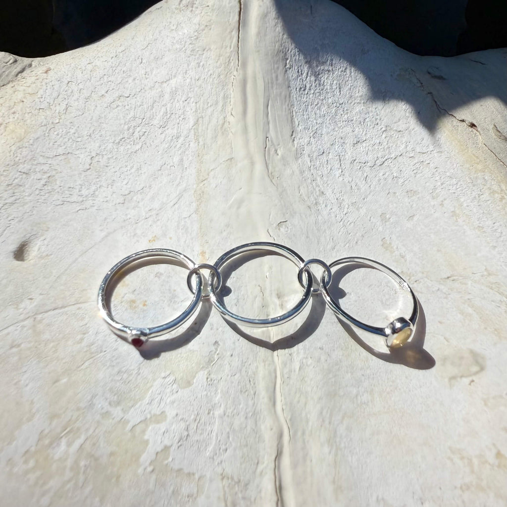 Silver ring with interlocking rings on a textured stone surface