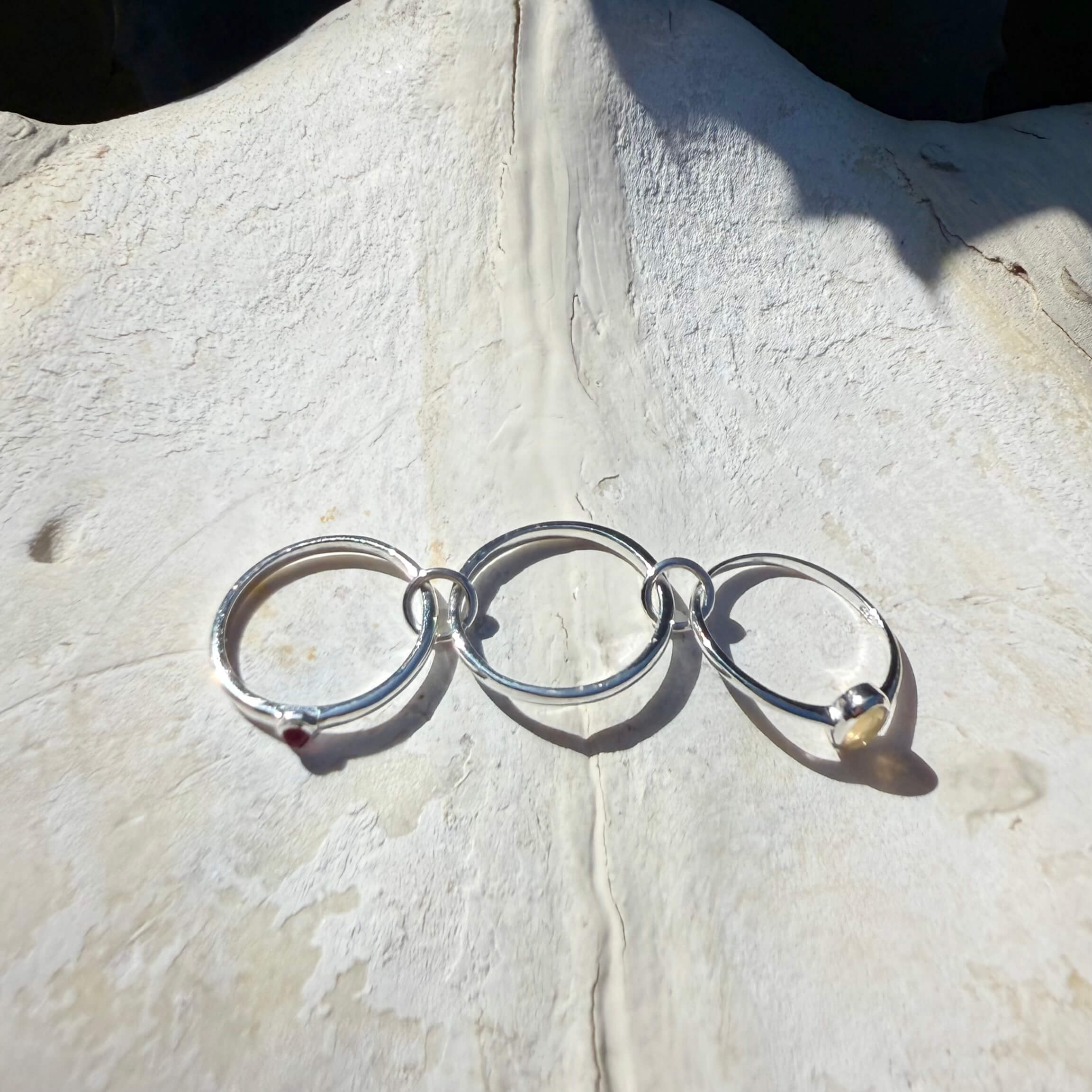 Silver ring with interlocking rings on a textured stone surface