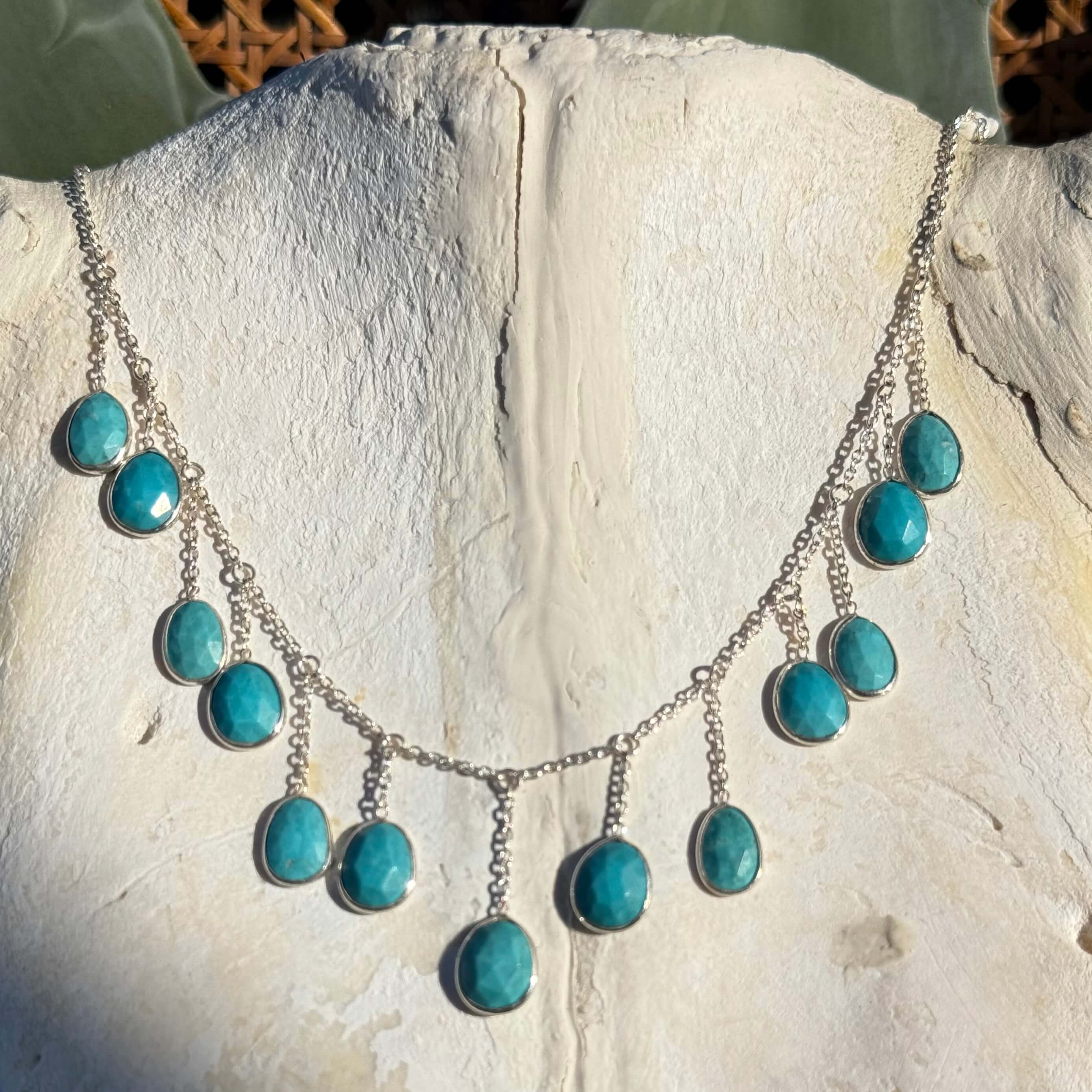 Silver necklace with turquoise stones on a textured white surface