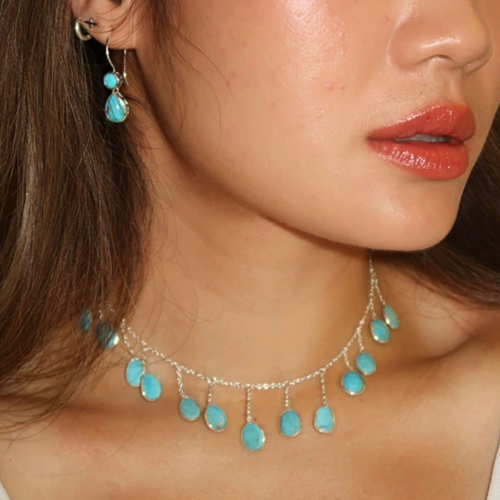 Close-up of a woman wearing turquoise earrings and a matching necklace.
