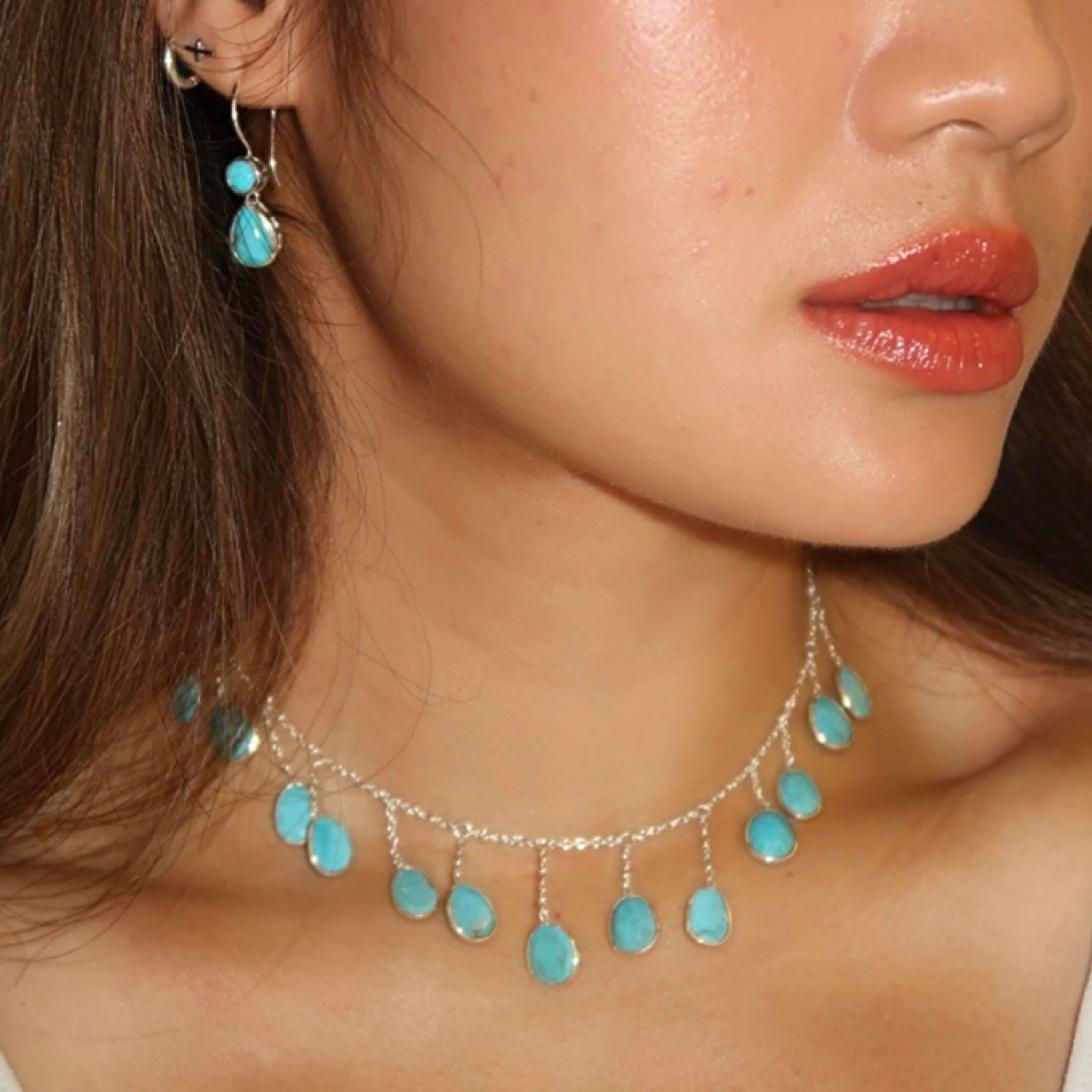 Close-up of a woman wearing turquoise earrings and a matching necklace.