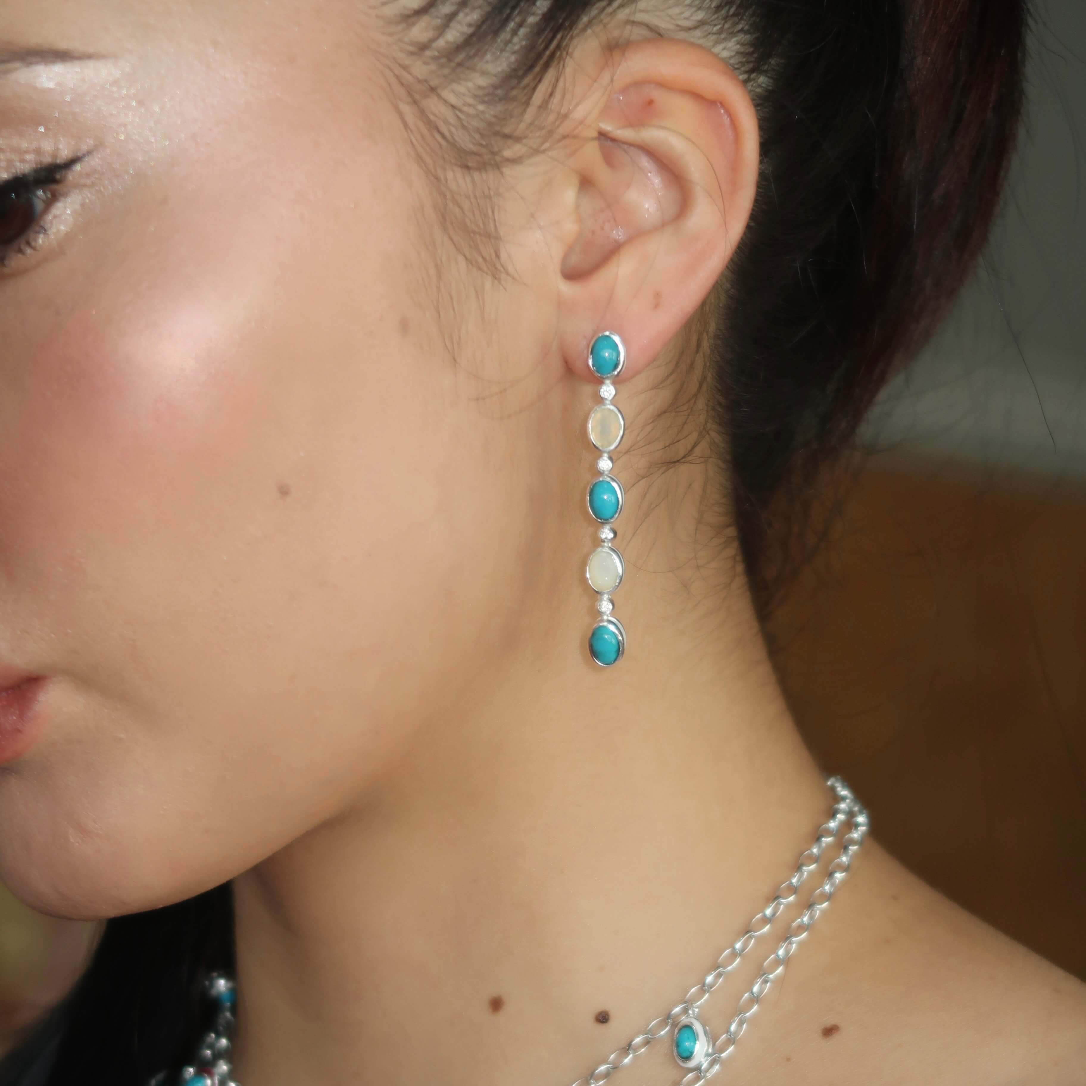 Close-up of a person wearing turquoise and silver earrings.