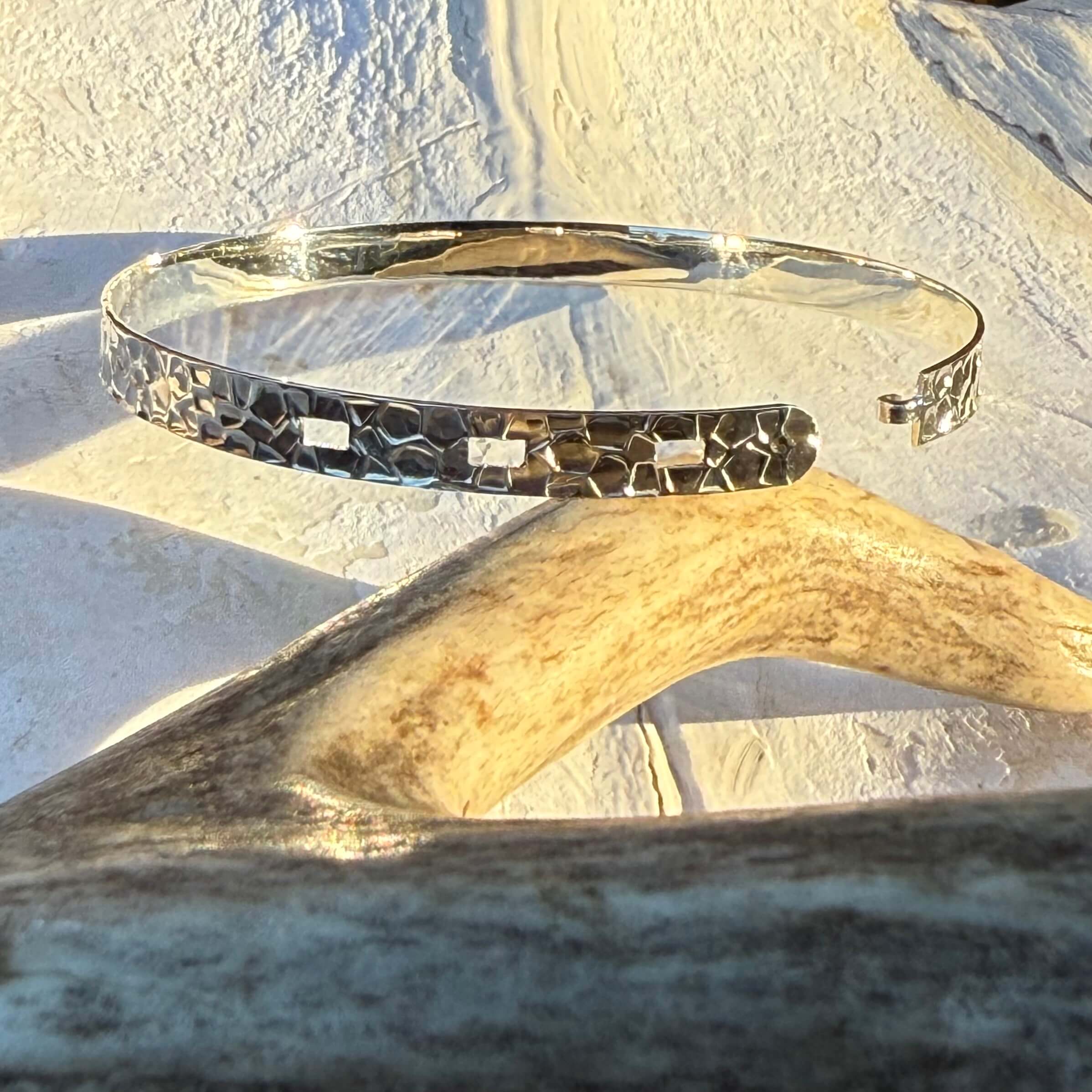 Silver bracelet with textured design on a light stone surface