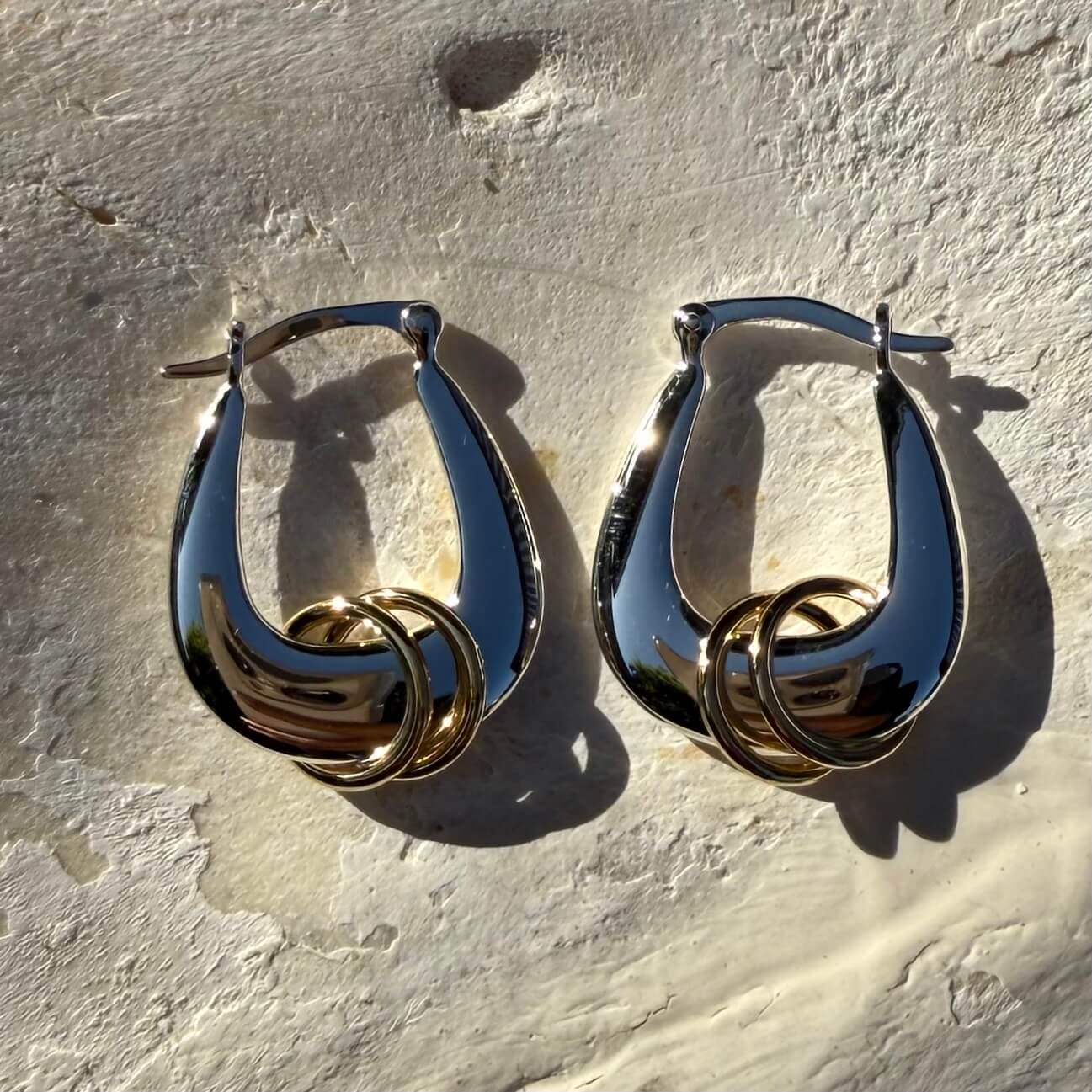 Pair of gold hoop earrings on a textured beige surface